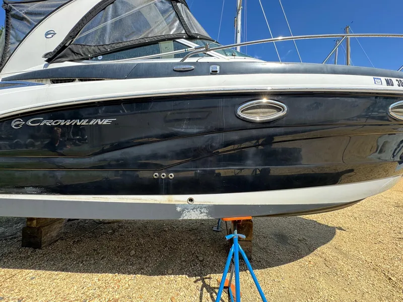 Slide: The Image of 2020 Crownline 264CR boat on dry dock, black hull, sunny day. - 14