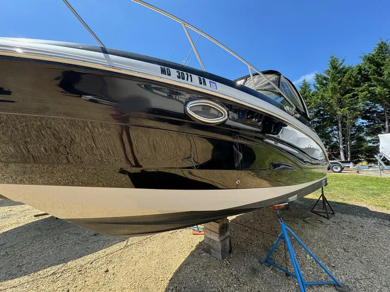 Slide: The Image of 2020 Crownline 264CR boat on stands, shiny black hull, clear blue sky. - 17