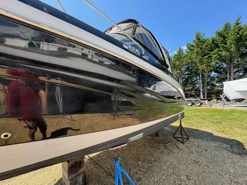 Slide: The Image of 2020 Crownline 264CR boat on dry land, side view with trees in background. - 18