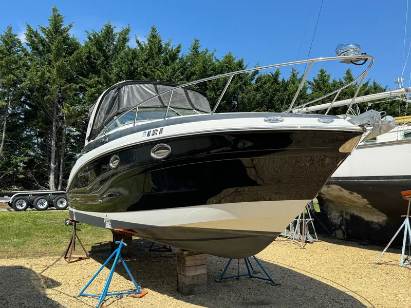 Slide: The Image of 2020 Crownline 264CR boat on stands, outdoors, with trees in the background. - 3