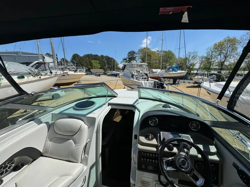 Slide: The Image of 2020 Crownline 264CR boat interior with steering wheel and seating, docked among other boats. - 30