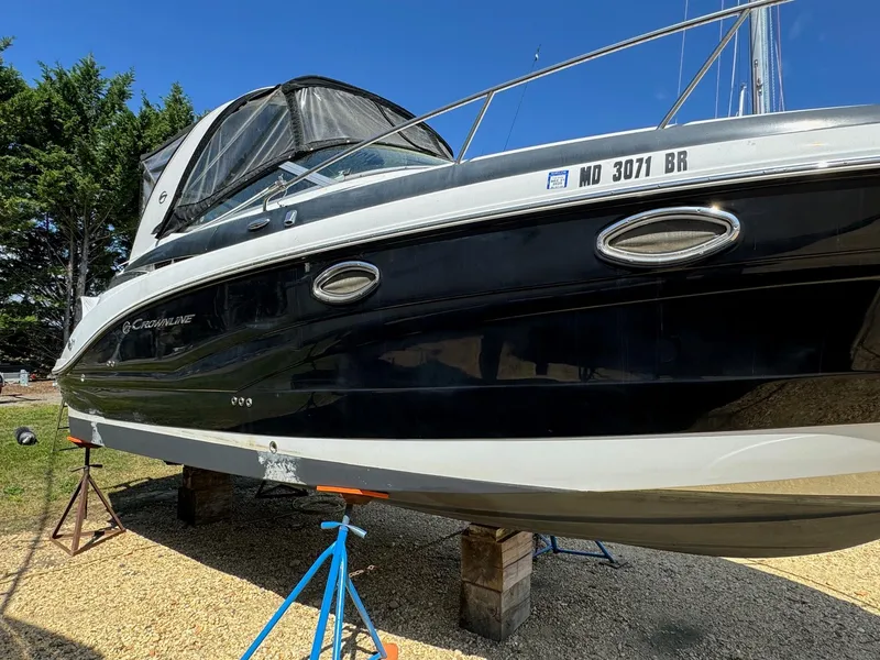 Slide: The Image of 2020 Crownline 264CR boat on stands, black and white exterior, sunny day. - 4