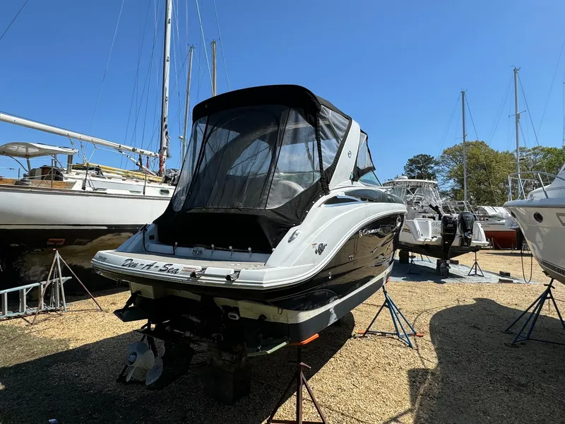 Slide: The Image of 2020 Crownline 264CR boat on stands, surrounded by other vessels, under clear blue sky. - 5
