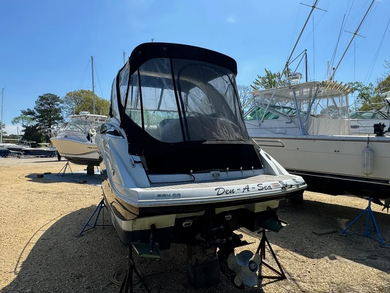 Slide: The Image of 2020 Crownline 264CR boat on stands, rear view with cover, in a marina. - 6