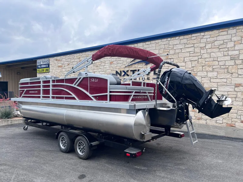 Slide: The Image of 2024 Bennington 22SV pontoon boat on trailer, red and silver design, parked outside. - 3