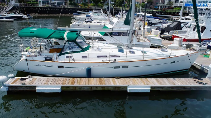 Slide: The Image of 2005 Beneteau 423 sailboat docked at marina, featuring green canopy and sleek design. - 2