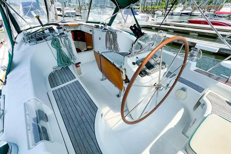 Slide: The Image of 2005 Beneteau 423 sailboat cockpit with wooden wheel and marina view. - 7
