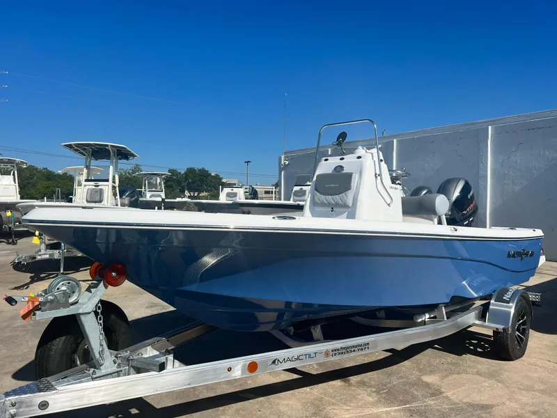 Slide: The Image of 2024 NauticStar 194 Bay boat on a trailer under a clear blue sky. - 7