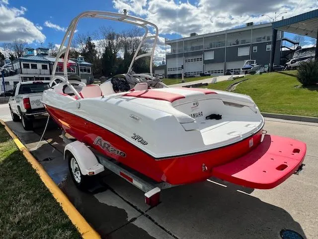 Slide: The Image of 2004 Yamaha Boats AR 210 on trailer, red and white, docked near marina. - 2