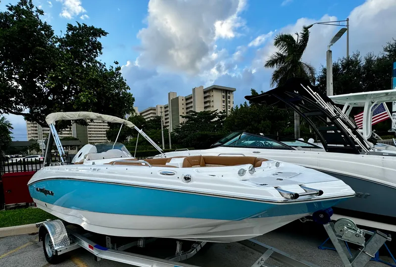 Slide: The Image of 2024 NauticStar 193SC Sport Deck boat on trailer, urban backdrop, blue sky. - 0