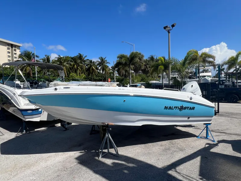 Slide: The Image of 2024 NauticStar 193SC Sport Deck boat on display in a marina under a clear blue sky. - 1