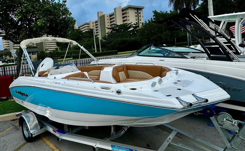 Slide: The Image of 2024 NauticStar 193SC Sport Deck boat on trailer, blue and white exterior, parked outdoors. - 19