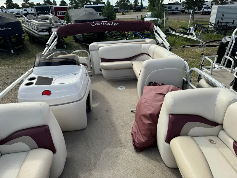 Slide: The Image of 2011 Sun Tracker Party Barge 21 with spacious seating and maroon accents, parked outdoors. - 6