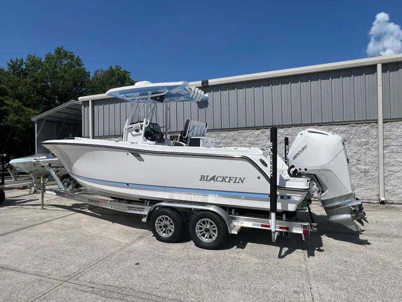Slide: The Image of 2024 Blackfin 252 CC boat on a trailer, parked outdoors. - 2