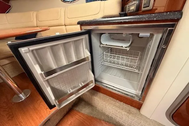 Slide: The Image of 2008 Formula 350 Sun Sport interior with open mini fridge, wooden flooring, and beige seating. - 26