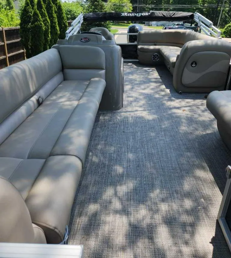Slide: The Image of 2024 Ranger Reata 200C pontoon boat interior with spacious seating and carpeted floor. - 2