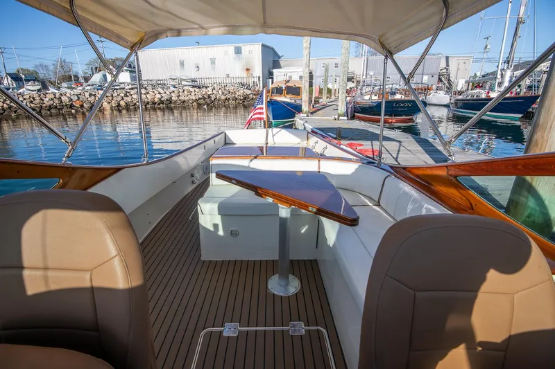 Slide: The Image of 2004 Hinckley Talaria 29 Runabout with elegant seating and wooden table, docked at marina. - 10