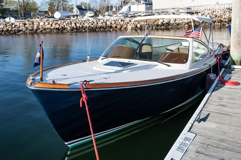 Slide: The Image of 2004 Hinckley Talaria 29 Runabout docked in a marina, featuring a sleek design and classic style. - 2