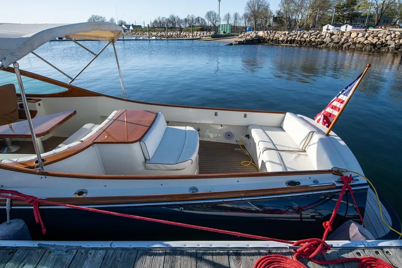 Slide: The Image of 2004 Hinckley Talaria 29 Runabout docked, featuring elegant seating and American flag. - 6