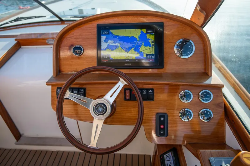 Slide: The Image of 2004 Hinckley Talaria 29 Runabout dashboard with wooden steering wheel and navigation display. - 15