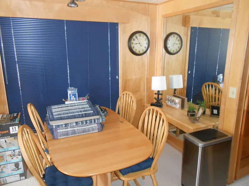 Slide: The Image of Dining area inside a 2001 Stardust Cruisers houseboat with wooden furniture and blue blinds. - 10