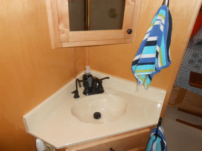 Slide: The Image of 2001 Stardust Cruisers houseboat bathroom sink with wooden cabinet and striped towel. - 12