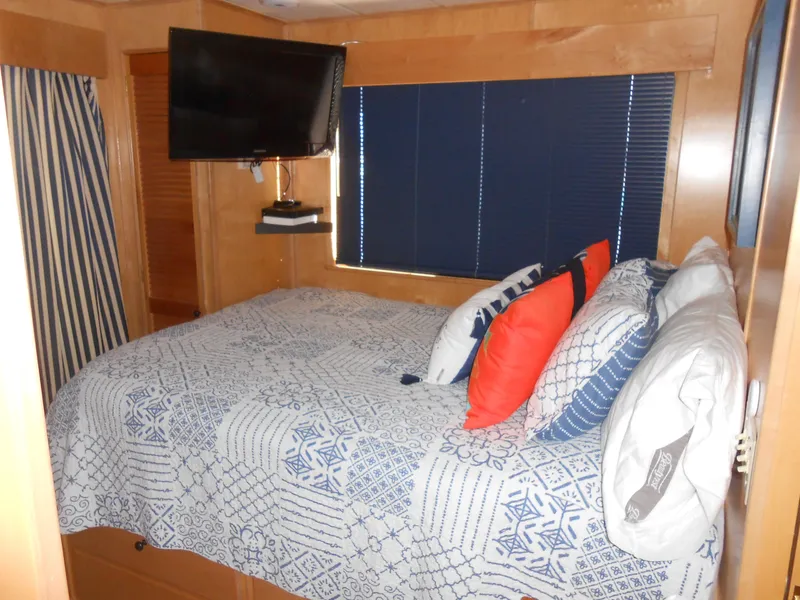 Slide: The Image of 2001 Stardust Cruisers houseboat bedroom with bed, TV, and blue blinds. - 14