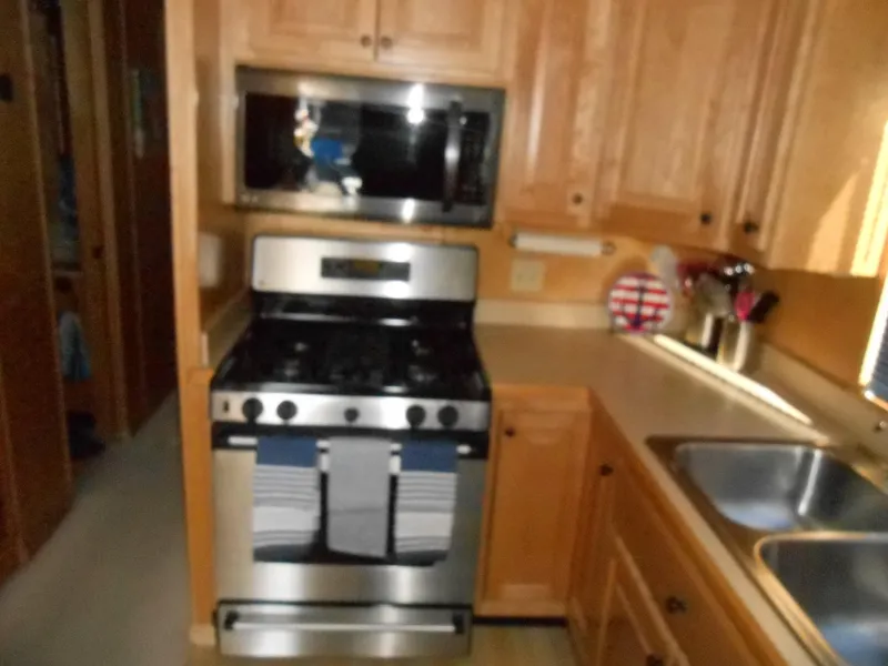 Slide: The Image of 2001 Stardust Cruisers houseboat kitchen with stainless steel stove, microwave, and wooden cabinets. - 8