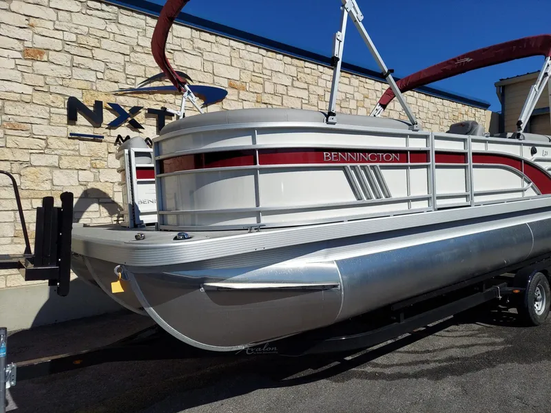 Slide: The Image of 2023 Bennington 23L pontoon boat on trailer, parked by stone wall. - 8