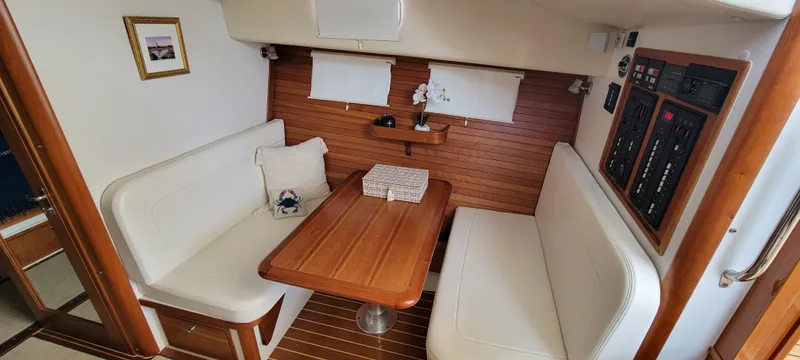 Slide: The Image of 2011 MJM 40z Downeast boat interior with white seating and wooden table. - 19