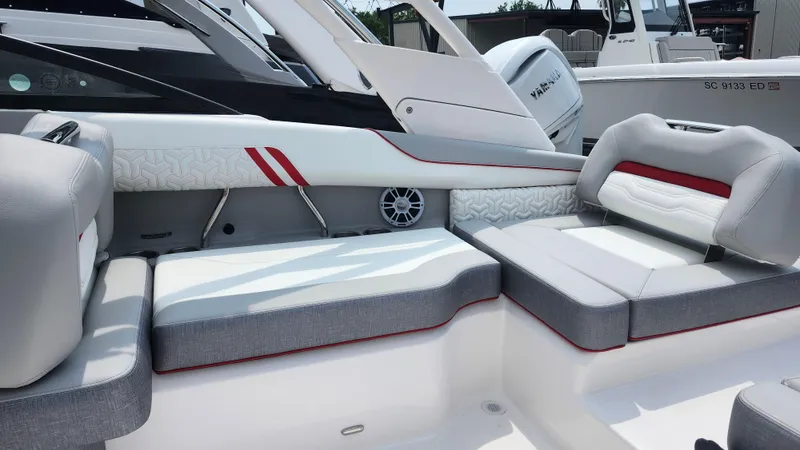 Slide: The Image of 2025 Regal LX2 boat interior with gray and white seating, red accents, and speaker. - 16