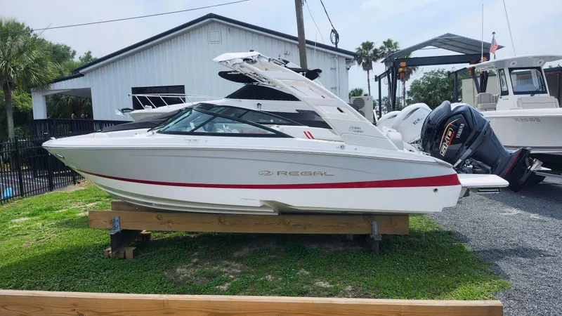 Slide: The Image of 2025 Regal LX2 boat displayed outdoors on wooden supports, near other boats. - 3