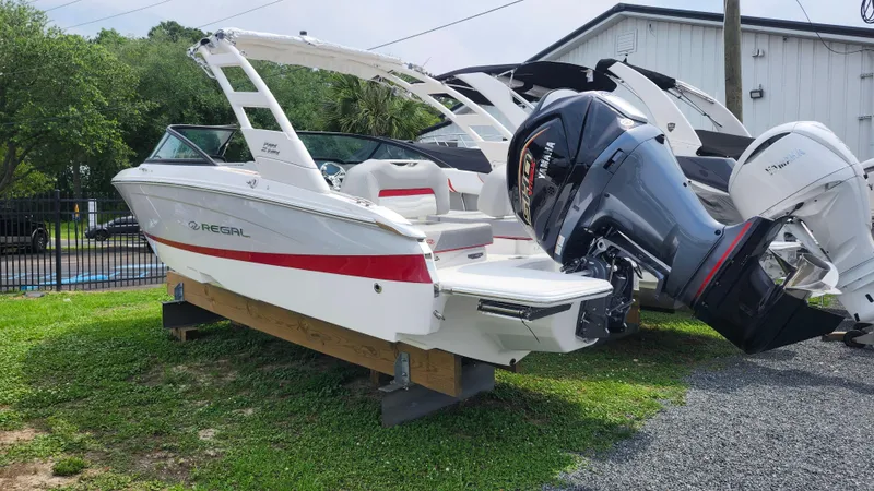 Slide: The Image of 2025 Regal LX2 boat with outboard motor displayed outdoors on grass. - 6
