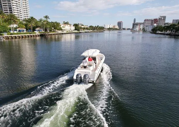 Slide: The Image of 2013 Pursuit C 260 Center Console boat cruising on a scenic waterway with cityscape. - 2