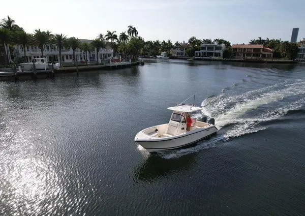 Slide: The Image of 2013 Pursuit C 260 Center Console boat cruising on a calm waterway near luxury homes. - 6