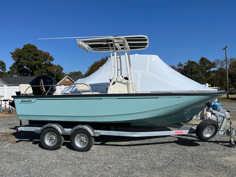 Slide: The Image of 2025 Boston Whaler 190 Montauk boat on trailer, parked outdoors under clear blue sky. - 27