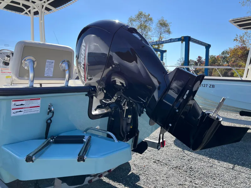 Slide: The Image of 2025 Boston Whaler 190 Montauk with powerful outboard motor, parked on gravel. - 30