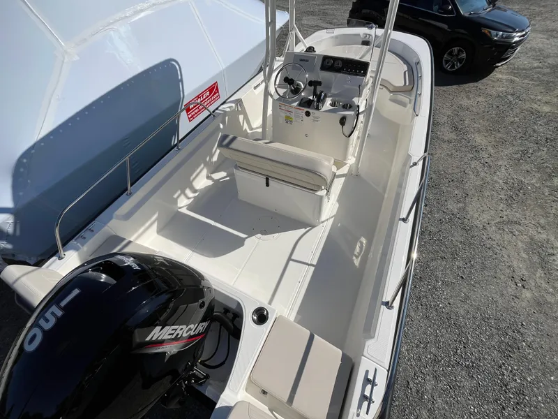 Slide: The Image of 2025 Boston Whaler 190 Montauk boat with Mercury engine, docked on gravel surface. - 4