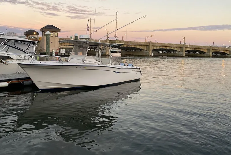Slide: The Image of 1999 Grady-White 306 Bimini boat docked near a bridge at sunset. - 2
