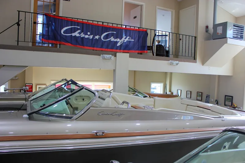 Slide: The Image of 2013 Chris-Craft Launch 32 boat displayed indoors with branded banner above. - 56