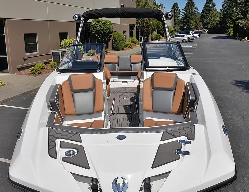 Slide: The Image of 2024 Scarab 255 ID boat with tan and gray seating, docked in a parking lot. - 18