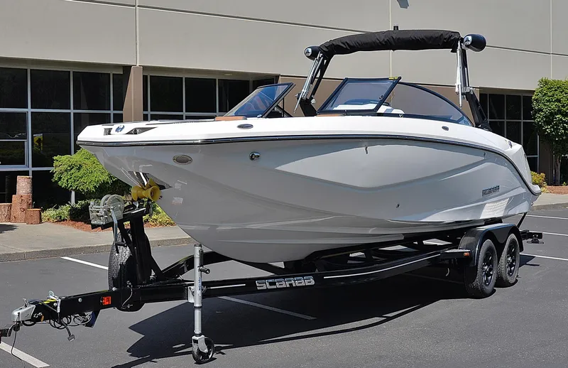 Slide: The Image of 2024 Scarab 255 ID boat on a trailer in a parking lot. - 2