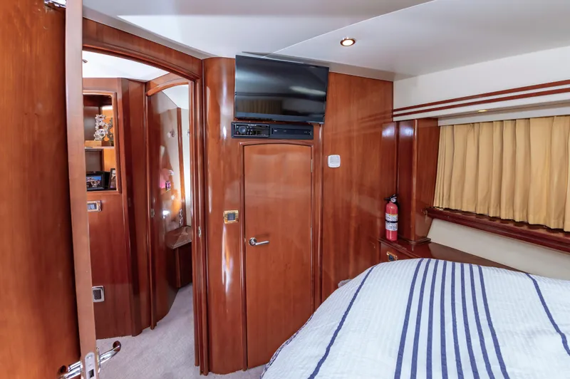Slide: The Image of 2004 Carver 56 Voyager SE bedroom with wood paneling, TV, and striped bedding. - 28