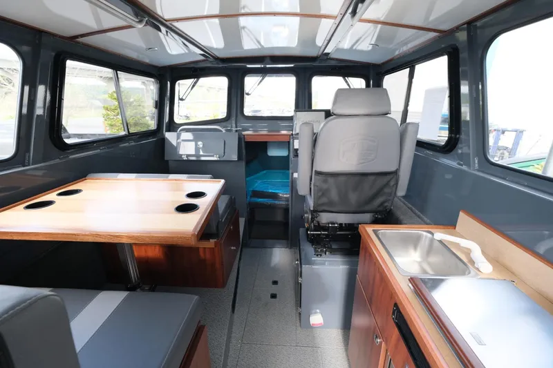 Slide: The Image of Interior of 2024 Hewescraft 250 Explorer boat, featuring seating, table, and kitchenette. - 10