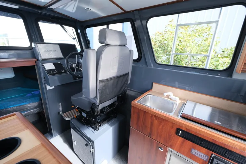 Slide: The Image of 2024 Hewescraft 250 Explorer interior with helm, seating, and kitchenette. - 12