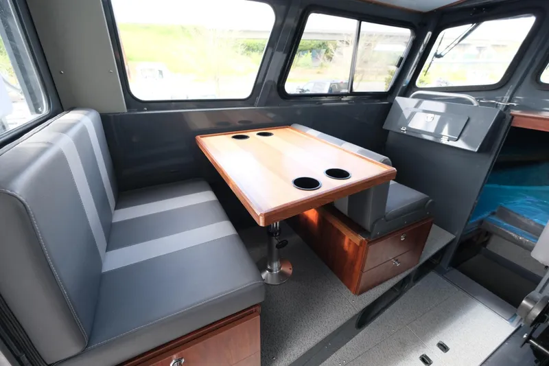 Slide: The Image of Interior of 2024 Hewescraft 250 Explorer, featuring a dining area with cushioned seating and table. - 11
