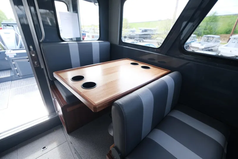 Slide: The Image of Interior of 2024 Hewescraft 250 Explorer with dining table and striped seating. - 17