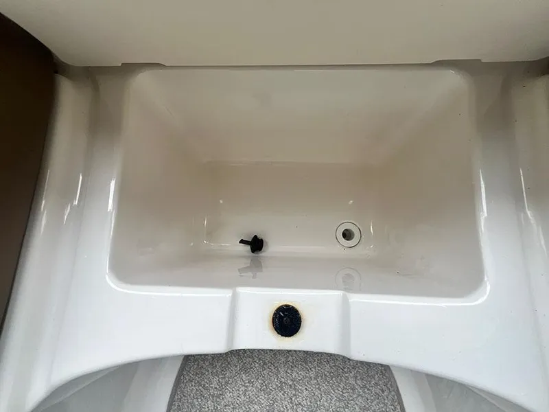 Slide: The Image of 2013 Chaparral 244 Sunesta boat storage compartment with drain plug. - 25