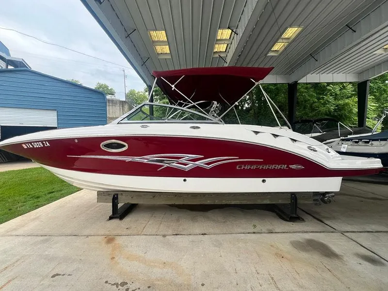 The Image of 2013 Chaparral 244 Sunesta boat with red and white exterior under a covered dock. - 3