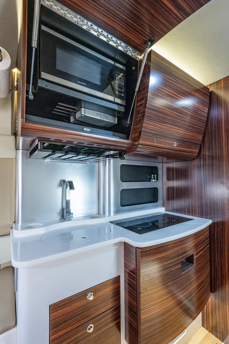 Slide: The Image of 2017 Scout 420 LXF boat kitchen with microwave, sink, and wooden cabinets. - 22